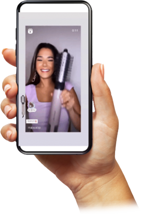 Hand holding a phone showing a video of an influencer using Remington